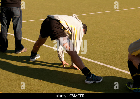 Player doing stretching exercise at club hockey match, UK Stock Photo
