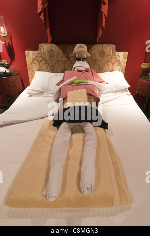 Folded towels representing a human figure laying on a hotel bed Stock Photo