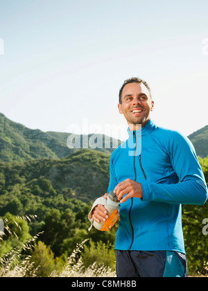 Athletic mixed race man drinking water outdoors Stock Photo