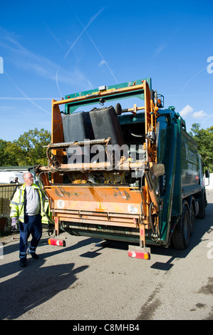 Refuse workers from Basildon Council in Essex working at rear of dust cart loading and emptying wheely (wheeled) bins into rear. Stock Photo