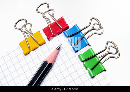 Black pencil on top of a notepad with squared paper and clips Stock Photo