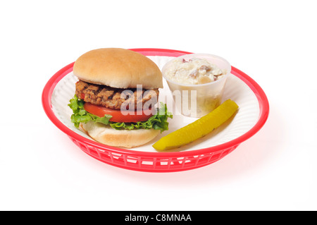 Grilled veggie burger with lettuce and tomato in bread roll in a red retro plastic basket on white background, cutout. Stock Photo