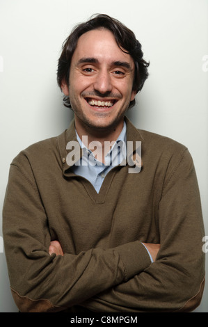 Portrait of happy young man with arms folded smiling on white background Stock Photo