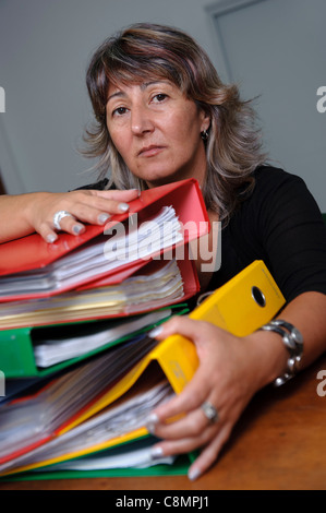 Female office worker on desk with stack of file folders on ring binders Stock Photo
