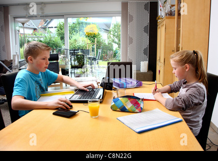Girl, 10 years old, boy, 13 years old, learning at home for school, doing homeworks. Stock Photo