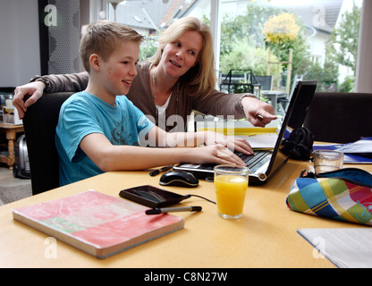 Brother and sister learning at home for school, getting assistance from their mother. Doing homework. Stock Photo