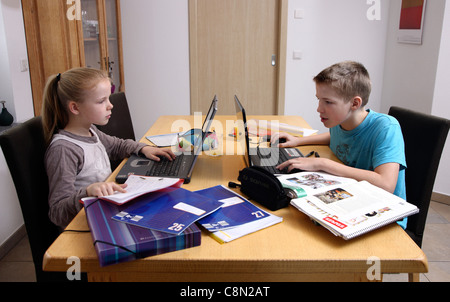 Girl, 10 years old, boy, 13 years old, learning at home for school, doing homeworks. Stock Photo