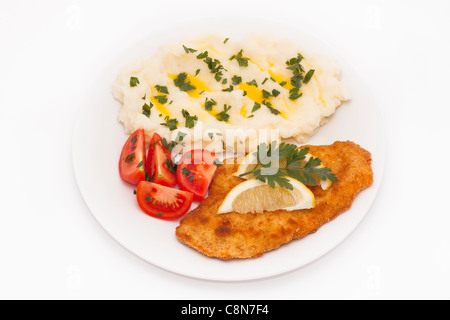 Schnitzel with lemon, tomatoes and potato mash, isolated on white background. Stock Photo