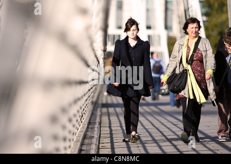 a low view along The Golden Jubilee Bridge, London, with two females and part of a boy walking towards the camera Stock Photo