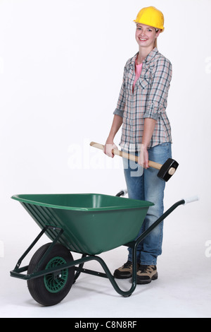 Tradeswoman placing a mallet in a wheelbarrow Stock Photo