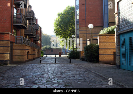 Empty cobbled road with bollards running between 2 blocks of modern flats Stock Photo