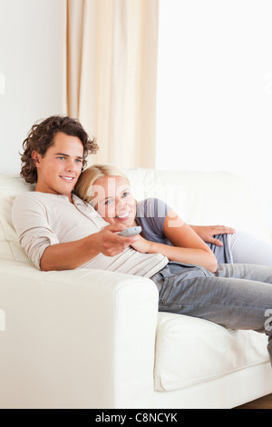 Portrait of a cute couple cuddling while watching TV Stock Photo - Alamy