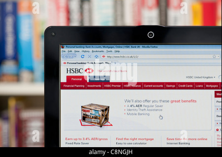 The HSBC website shot against a bookcase background (Editorial use only: print, TV, e-book and editorial website). Stock Photo