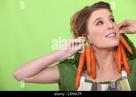 a female cook wearing carrots as earrings Stock Photo