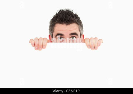 Man hiding behind white board Stock Photo