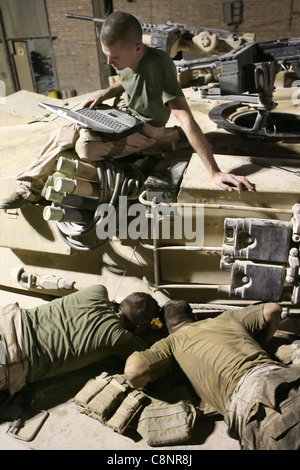 Night crew tank mechanics troubleshoot a tank engine with help from an electronic manual at Camp Habbaniyah, Iraq June 29. Marines of Company A, 2nd Tank Battalion are supporting the grunts of 3rd Battalion, 5th Marine Regiment by maintaining a constant presence with their M1A1 Abrams Main Battle Tanks along the main highways near Habbaniyah, Iraq to deter improvised explosive device placement and provide support with their 120 mm main guns if needed. Stock Photo