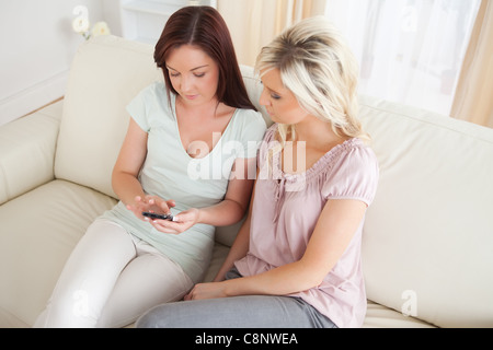Cute women lounging on a couch with a phone Stock Photo