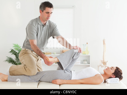 Chiropractor stretching young woman's leg Stock Photo