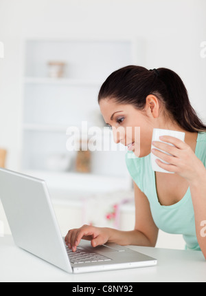 Young woman with cup of coffee at by her laptop Stock Photo