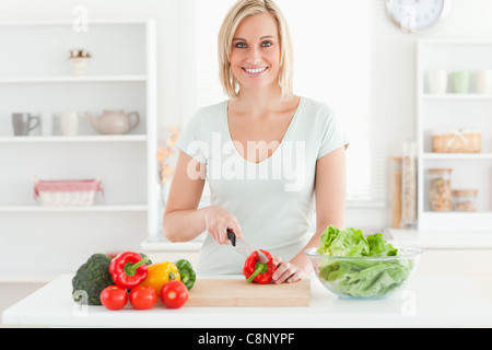Young woman cutting vegetables smiles into camera Stock Photo