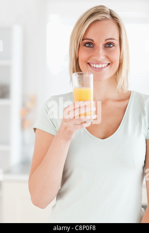 Charming woman holding glass filled with orange juice looking at the camera Stock Photo