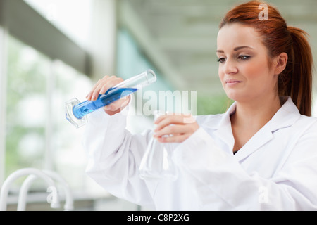 Scientist pouring liquid in an Erlenmeyer flask Stock Photo