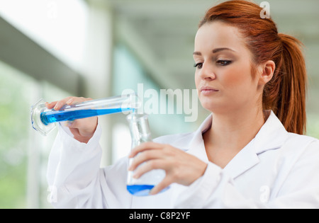 Young scientist pouring blue liquid in an Erlenmeyer flask Stock Photo