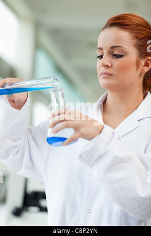 Portrait of a scientist pouring blue liquid in an Erlenmeyer flask Stock Photo