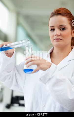 Portrait of a cute scientist pouring blue liquid in an Erlenmeyer flask Stock Photo