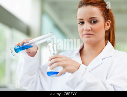 Cute scientist pouring blue liquid in an Erlenmeyer flask Stock Photo