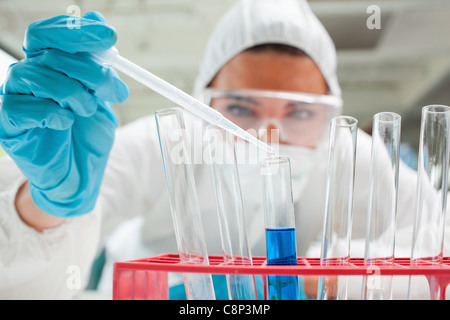 Close up of a protected scientist dropping liquid in a test tube Stock Photo