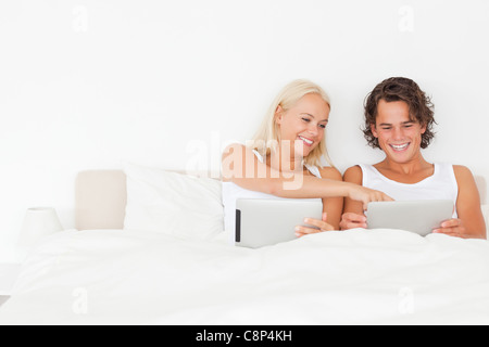 Laughing couple using tablet computers Stock Photo