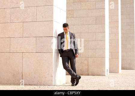 Sad businessman next to some wall looking down Stock Photo
