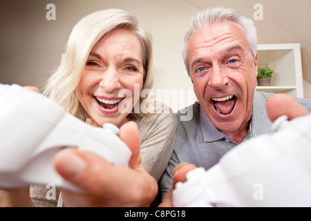 Senior couple, man and woman, laughing & having fun playing video console games together. Stock Photo