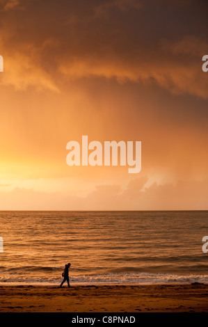 a man walking alone on the beach at the end of the day Aberystwyth seaside, october afternoon, Wales UK Stock Photo