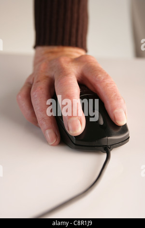 An old woman's hand using a computer mouse. Stock Photo
