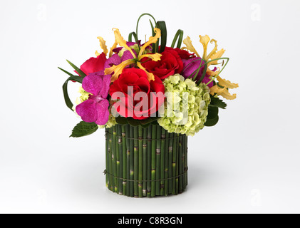 A colorful bouquet of flowers in a vase. Red roses, cream hydrangea, yellow orchid [Laelia], purple orchid [Vanda] Stock Photo