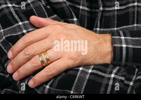bigamy symbol - male hand with two weeding rings Stock Photo