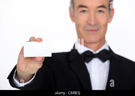 Silver service waiter holding up a business card Stock Photo