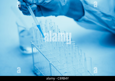 Protected hand dropping dangerous liquid in test tubes Stock Photo