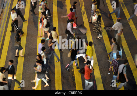 Pedestrians cross the street at a cross-walk during the busy rush hour. Stock Photo