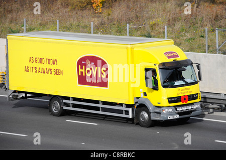 Hovis bread food supply chain rigid body delivery lorry yellow truck displaying poppy logo & advertising driving along M25 motorway Essex England UK Stock Photo