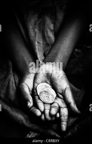 Indian street girl begging for money with rupee coins in her hand.Black and White Stock Photo