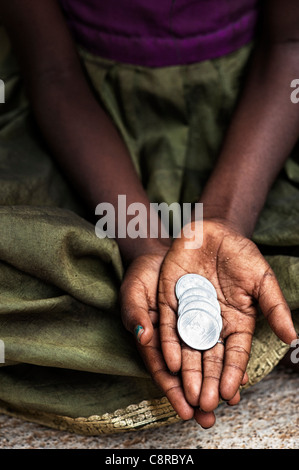 Indian street girl begging for money with rupee coins in her hand. Stock Photo