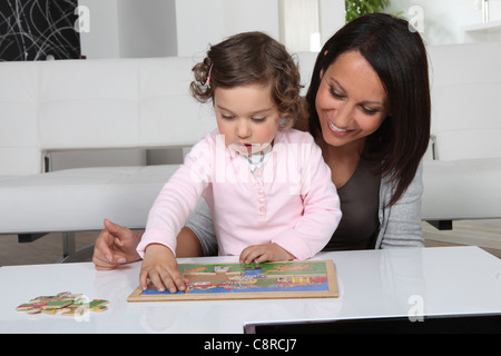 Little girl and woman doing puzzle Stock Photo