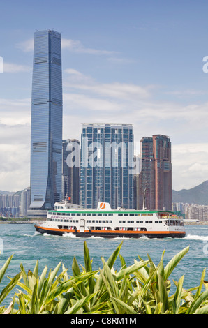 A ferry leaves Victoria Harbour past the Hong Kong waterfront development of Union Square, West Kowloon, Hong Kong, China Stock Photo
