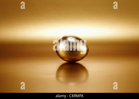 Shiny golden egg against golden background Stock Photo