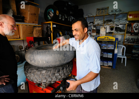Africa, Tunisia, Nabeul. Local tunisian mechanic repairing a flat 900x16 Michelin XS sand tyre belonging to travellers ... Stock Photo