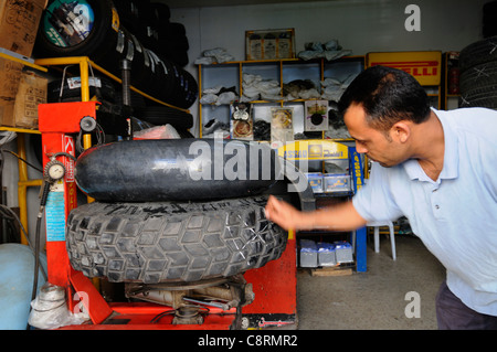 Africa, Tunisia, Nabeul. Local tunisian mechanic while repairing a tyre puncture on a Michelin XS sand tyre. Stock Photo