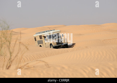 Africa, Tunisia, nr. Tembaine. Desert traveller driving his ex-army 1966 Land Rover Series 2a Ambulance camper conversion ... Stock Photo